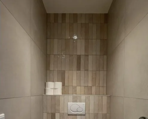Staande glanzende wandtegels in een gerenoveerd toilet